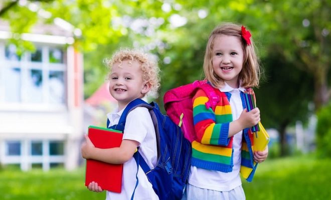 παιδιά αγοράκι και κοριτσάκι με πολύχρωμες τσάντες στο δρόμο για το σχολείο